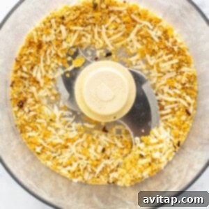 Food processor containing corn flakes and spices being processed for breadcrumb topping.