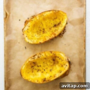 Two halves of baked spaghetti squash on a baking sheet, illustrating the roasting process.