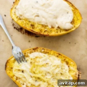 Two spaghetti squash boats filled with creamy cheese sauce on a baking sheet, ready for topping.