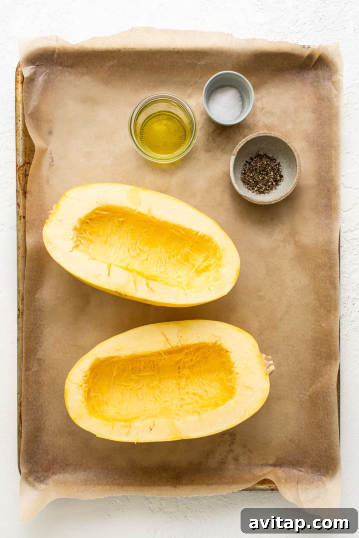 Fresh ingredients for spaghetti squash mac and cheese, including squash, cheese, and herbs, neatly arranged on a baking sheet.