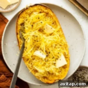 Roasted spaghetti squash on a plate, ready to be fluffed into tender strands.