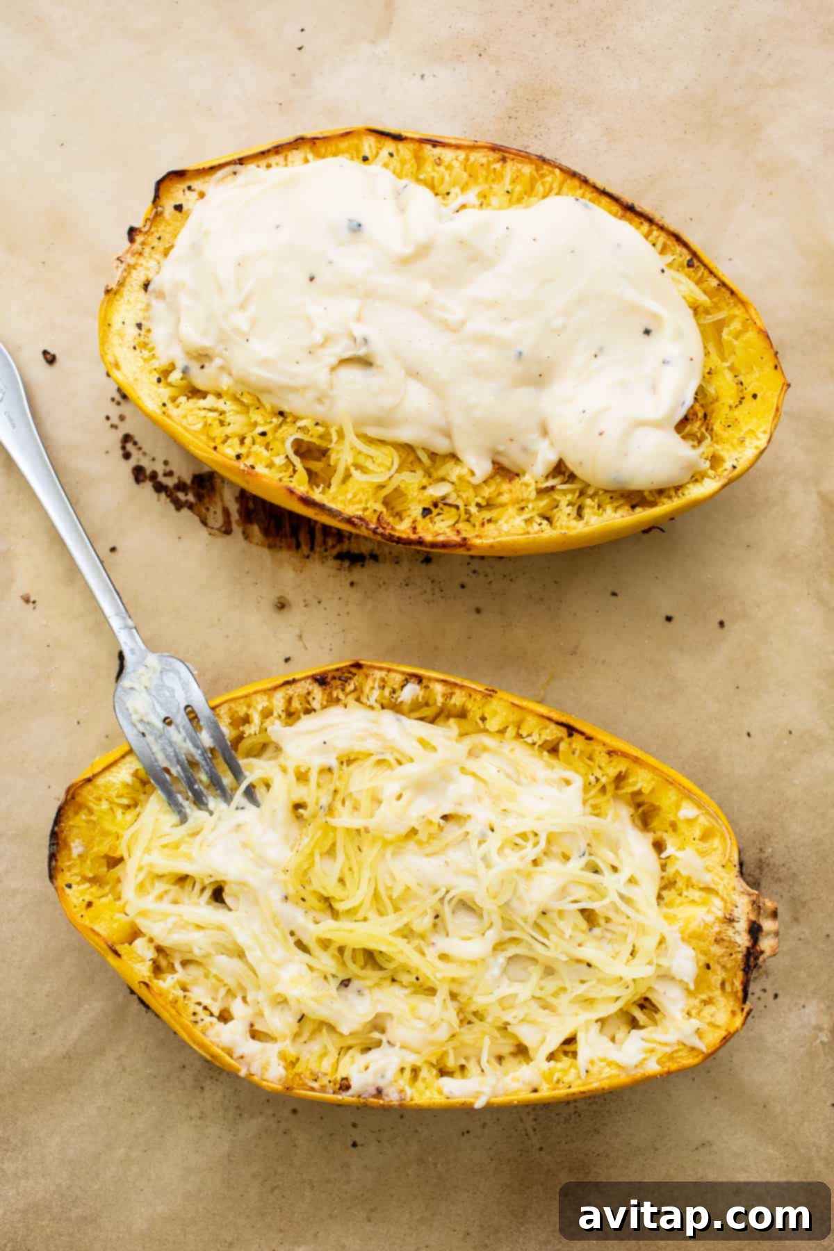 Spaghetti squash halves filled with creamy cheese sauce and ready for the crispy topping, on a baking sheet.