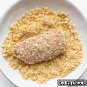 Gourmet Stuffed Pork Chops 9 A stuffed pork chop being dipped into Ritz cracker crumbs.