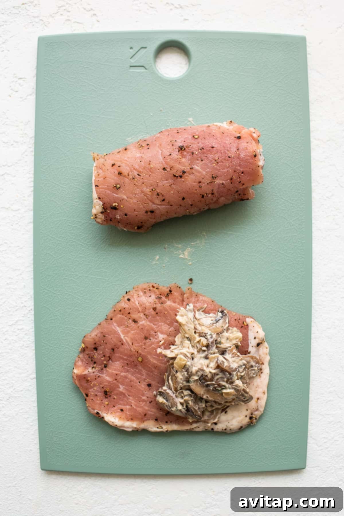 Hands-On: Stuffing Pork Chops with Cheesy Mushroom Filling A cutting board with a pork chop being stuffed with mushroom mixture.