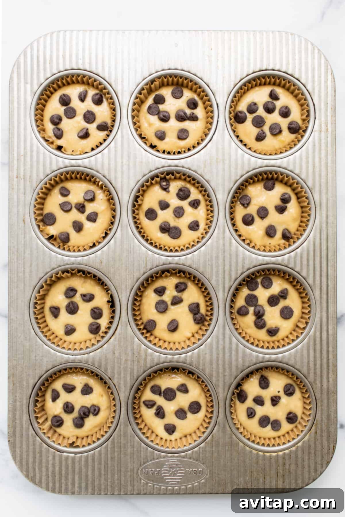 Freshly baked banana bread muffins cooling in a muffin tin.