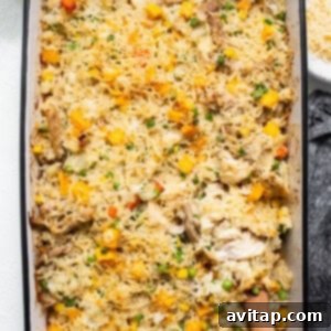 A hot chicken and vegetable casserole, steaming in a baking dish with a wooden spoon inserted.