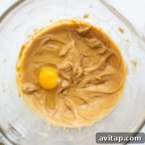 A bowl of peanut butter with an egg in it.