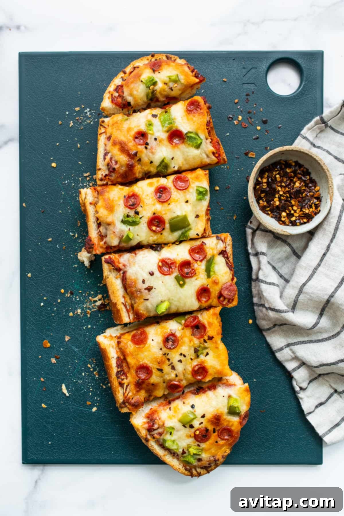 Easy Homemade French Bread Pizza with Pepperoni and Green Peppers French bread pizza on a cutting board, ready to serve.