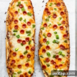 Two slices of French bread pizza on a baking sheet, freshly baked.