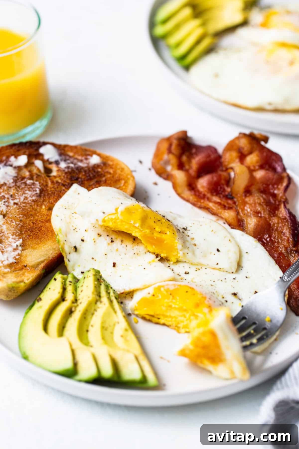 A perfectly cooked over hard egg served on a plate with crispy bacon, garnished for a classic breakfast.