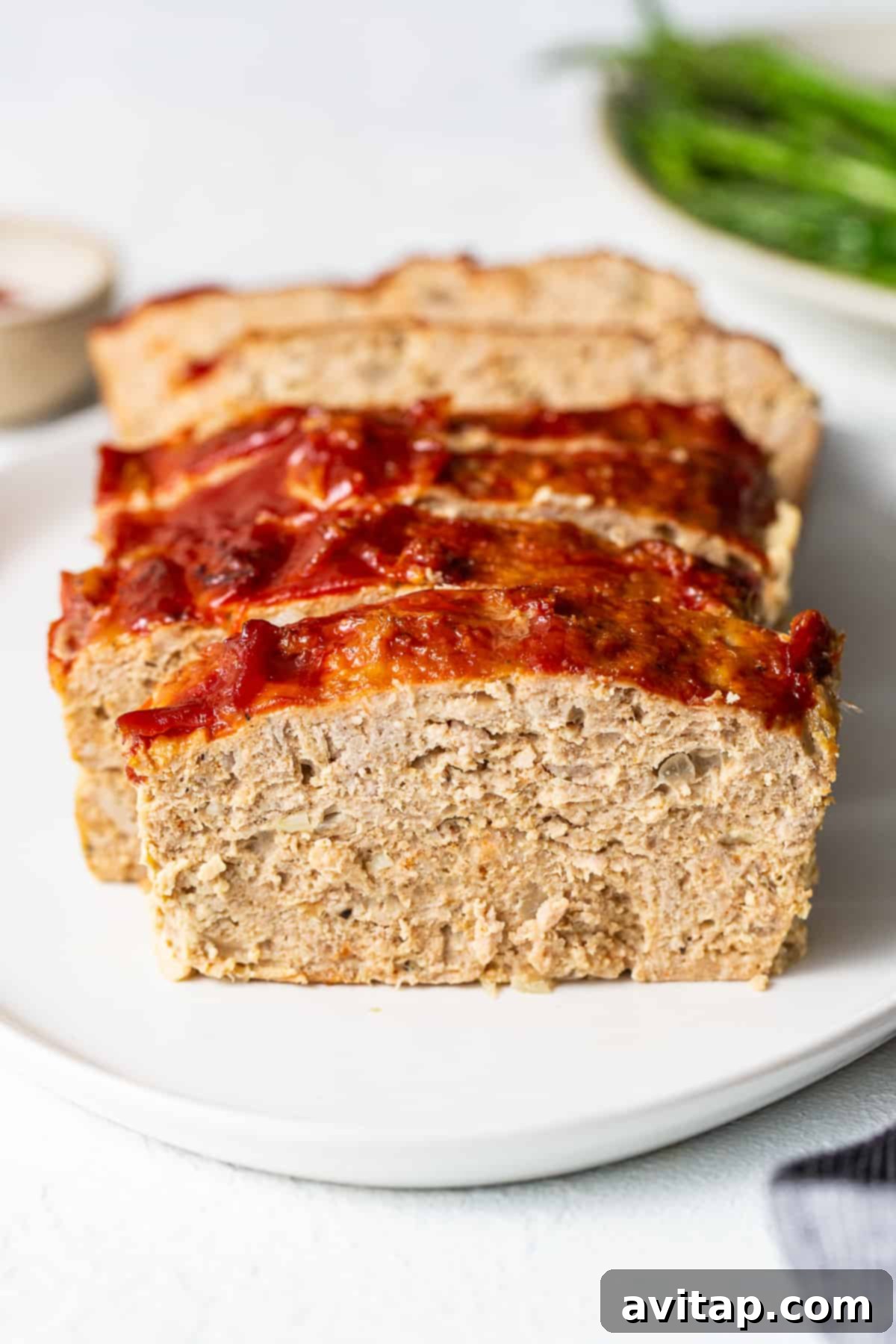 Enjoy a savory slice of homemade turkey meatloaf. Perfectly sliced ground turkey meatloaf presented beautifully on a plate.