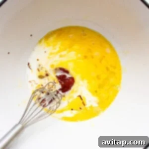 An egg in a bowl with a whisk, ready for mixing.