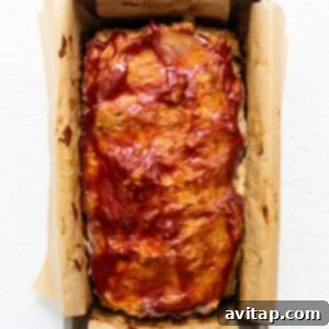 Meatloaf in a baking pan with BBQ sauce on top, after partial baking.