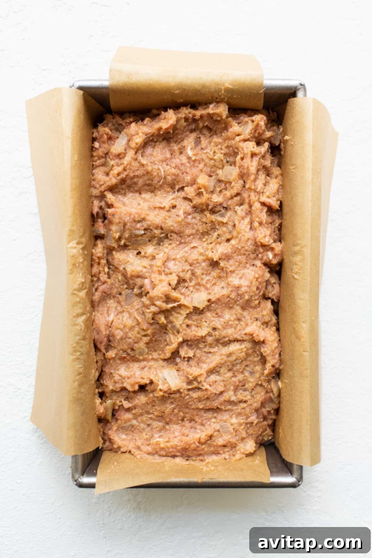 Prepared turkey meatloaf ready for the oven. Ground turkey meatloaf mixture neatly packed into a loaf pan before baking.