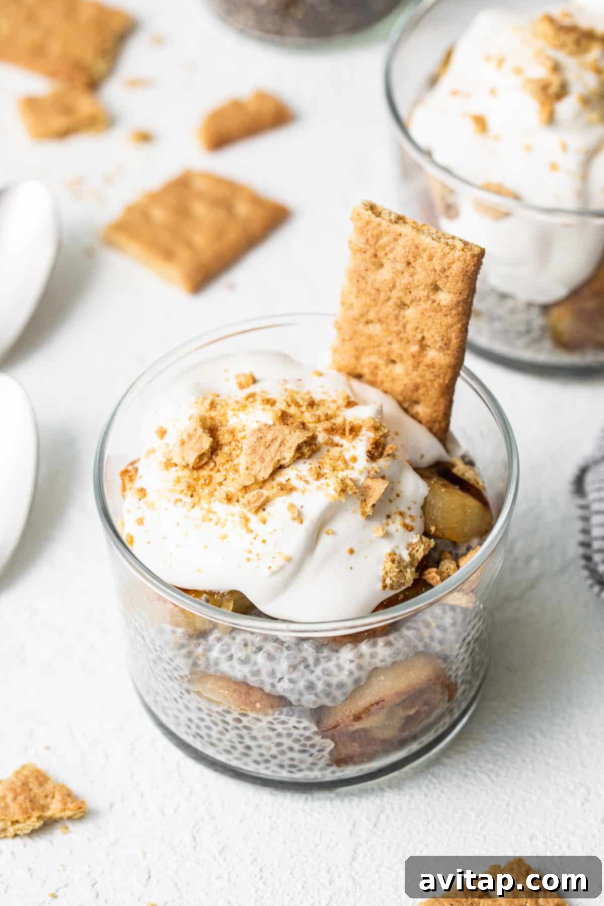 A glass of banana cream pie chia seed pudding topped with caramelized bananas and graham crackers, ready to eat.
