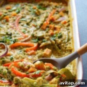A curry quinoa casserole garnished with vegetables and served with a spoon.