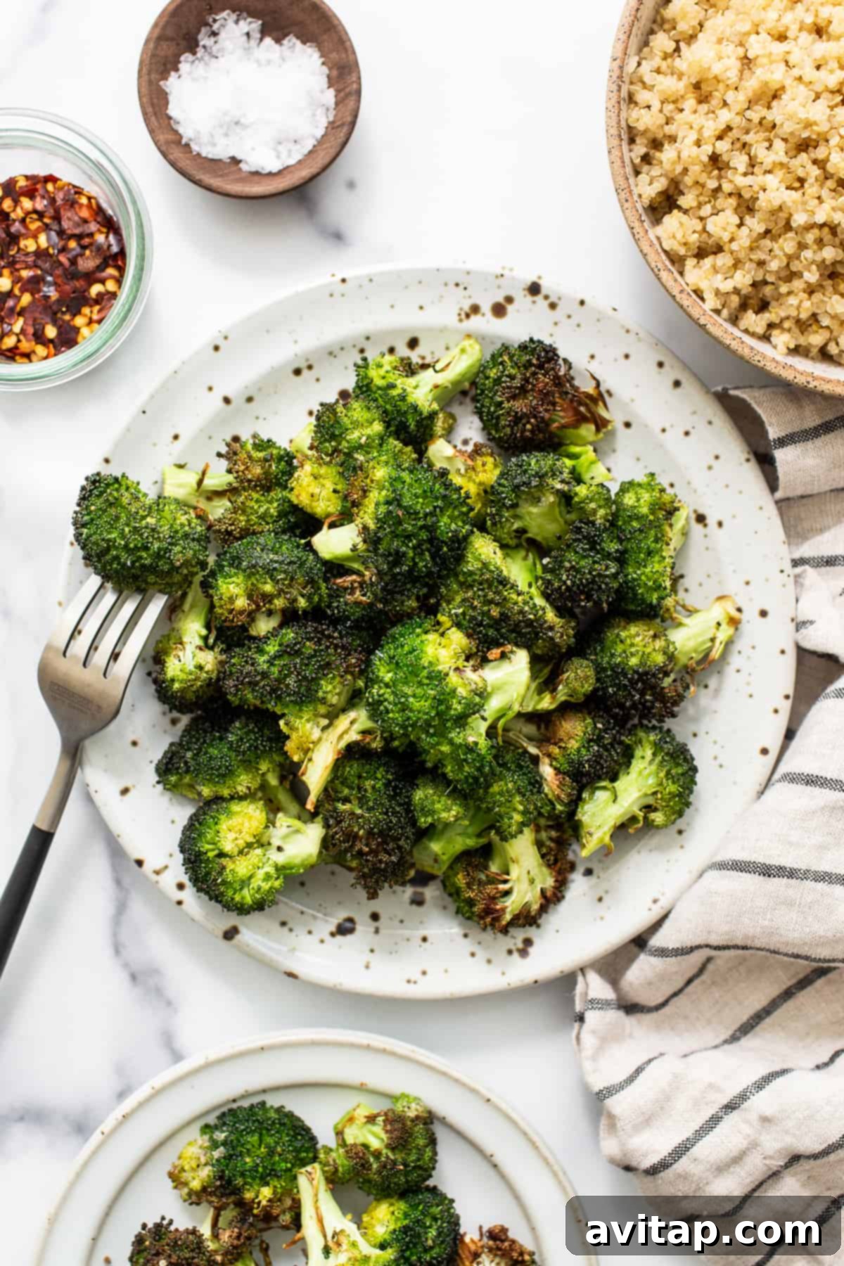 Air fryer broccoli on a plate, garnished with lemon wedges.
