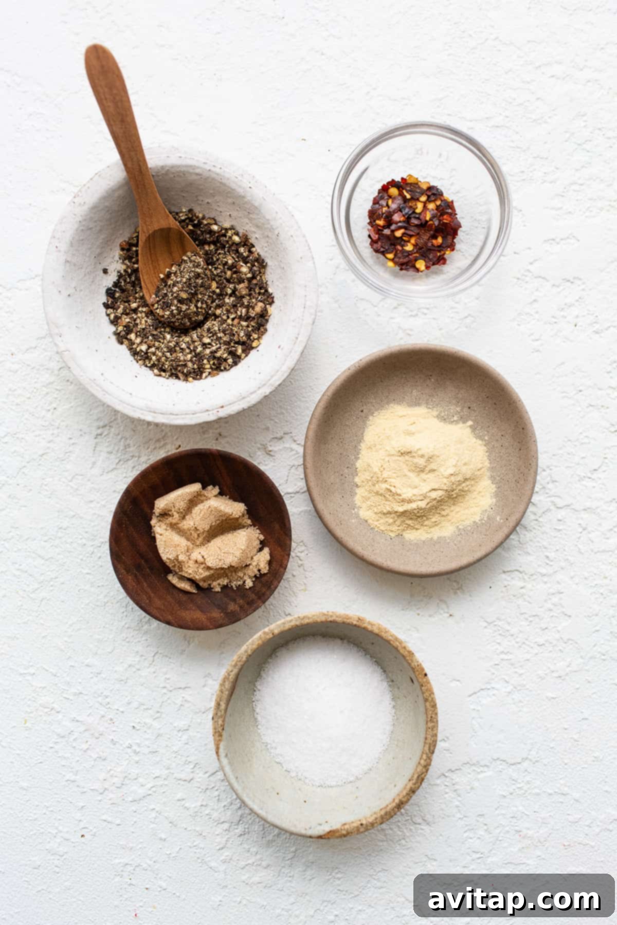 Prepare your homemade steak seasoning with these essential spices. Individual bowls holding each ingredient for steak seasoning, neatly arranged before mixing.