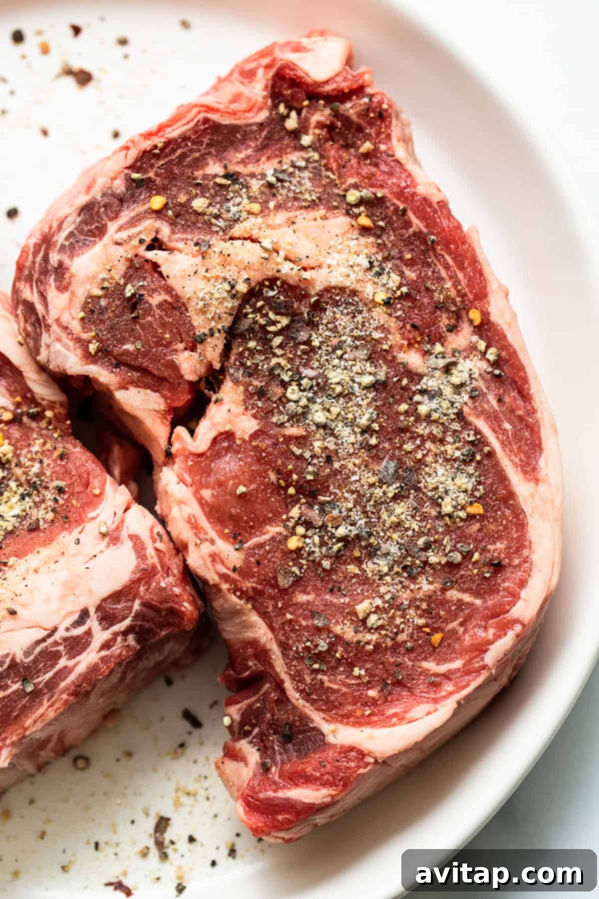 Raw steak beautifully coated with homemade seasoning, prepped for cooking. Steak seasoning sprinkled generously on a raw steak, ready for cooking.