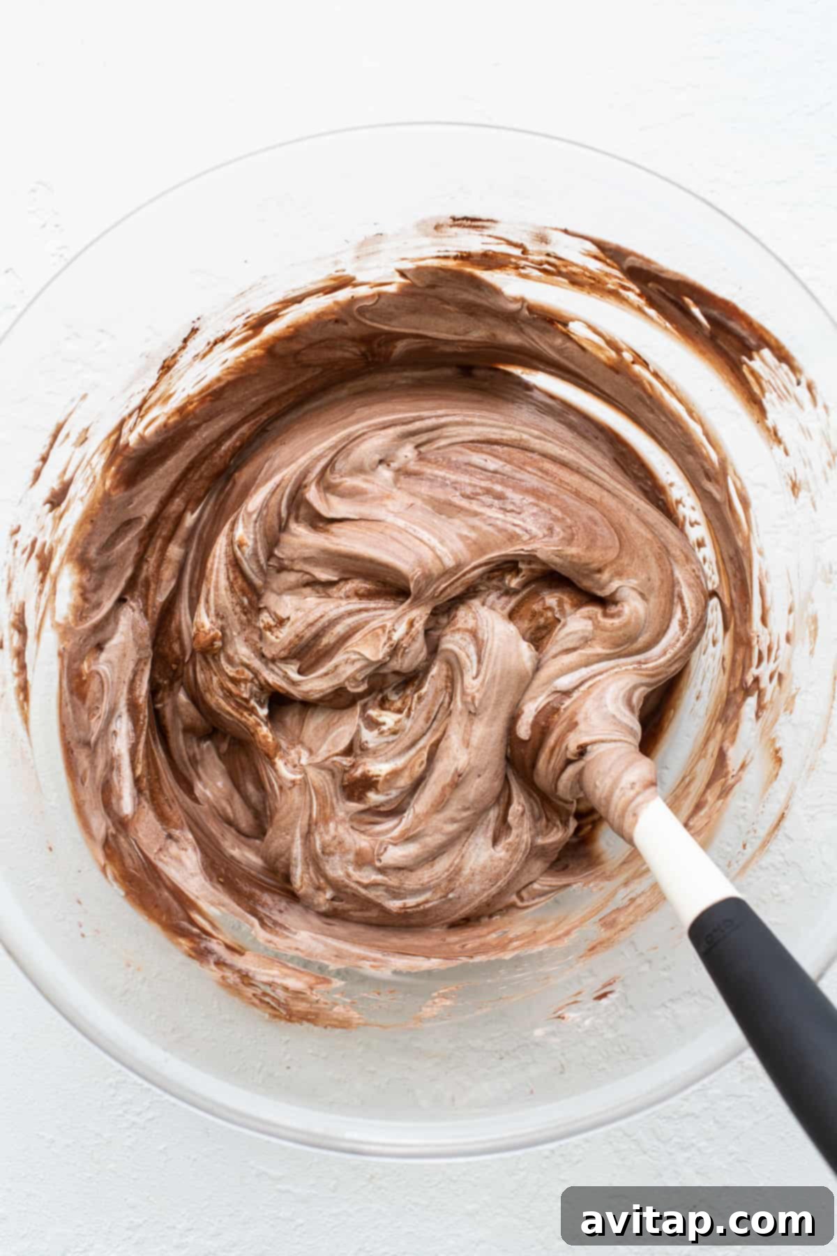 A bowl of the chocolate yogurt base mixed with granola, appearing thick and ready for spreading onto a baking sheet.