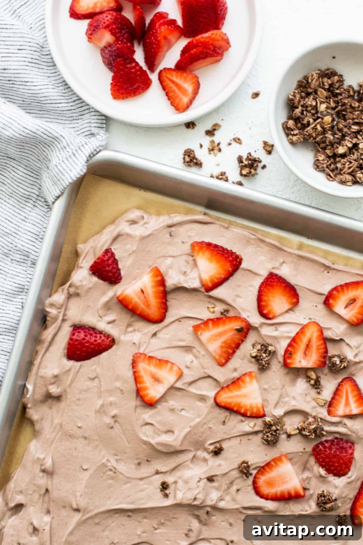 Close-up of frozen yogurt bark topped with vibrant sliced strawberries and a delicate hint of chocolate drizzle, showcasing its appealing texture.