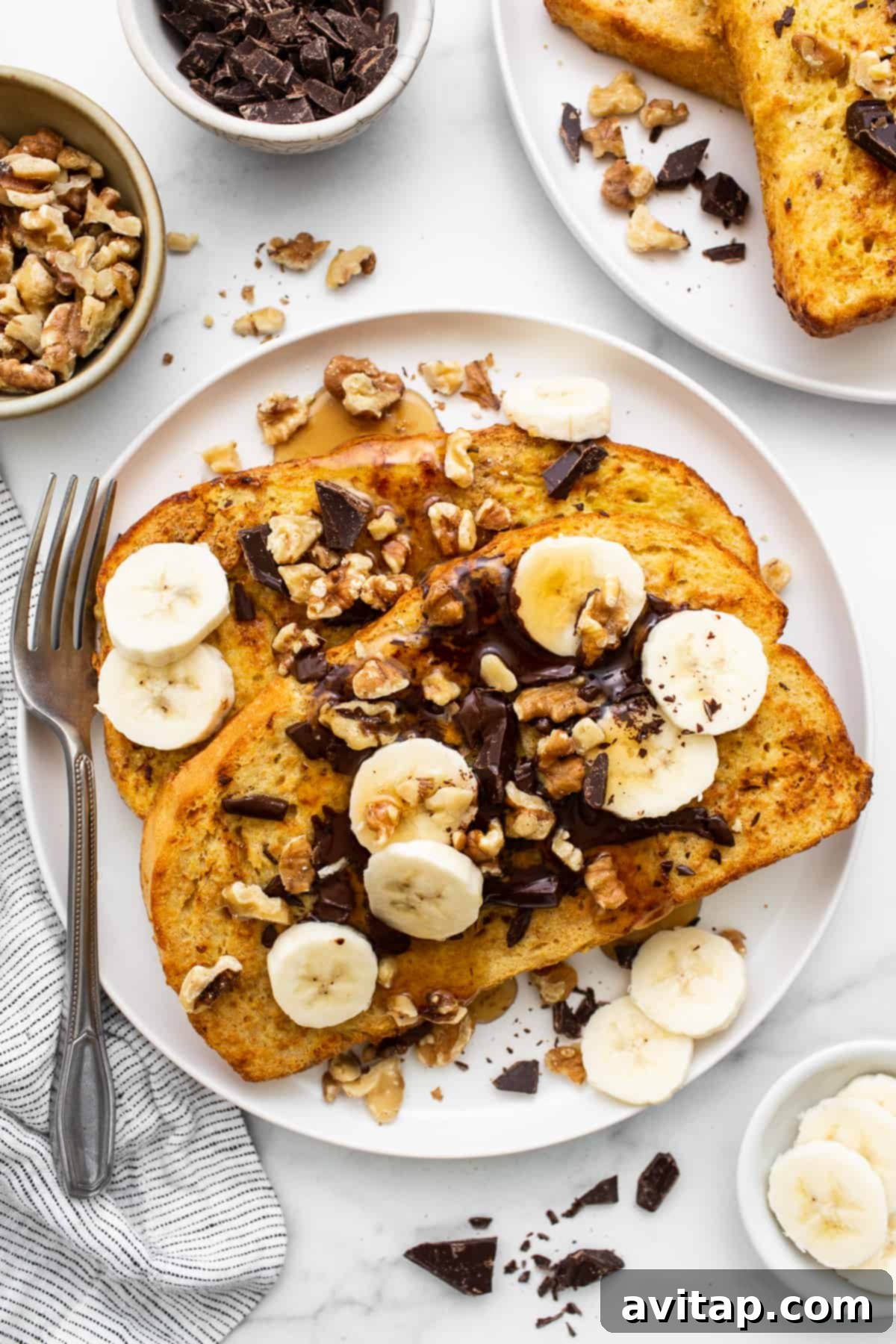 Air fryer chunky monkey french toast artfully arranged on a plate, garnished with melted chocolate, roasted walnuts, and fresh banana slices.