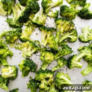 Broccoli florets seasoned with salt and pepper on a baking sheet.
