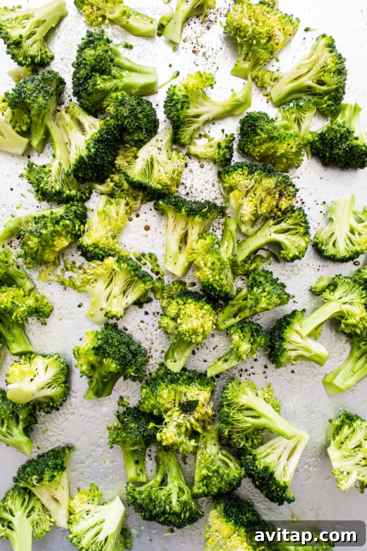Freshly roasted broccoli florets spread evenly on a sheet pan, ready to be served.