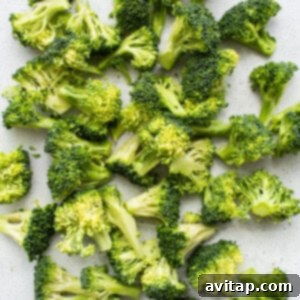 A pile of chopped broccoli on a white surface, ready for oiling.