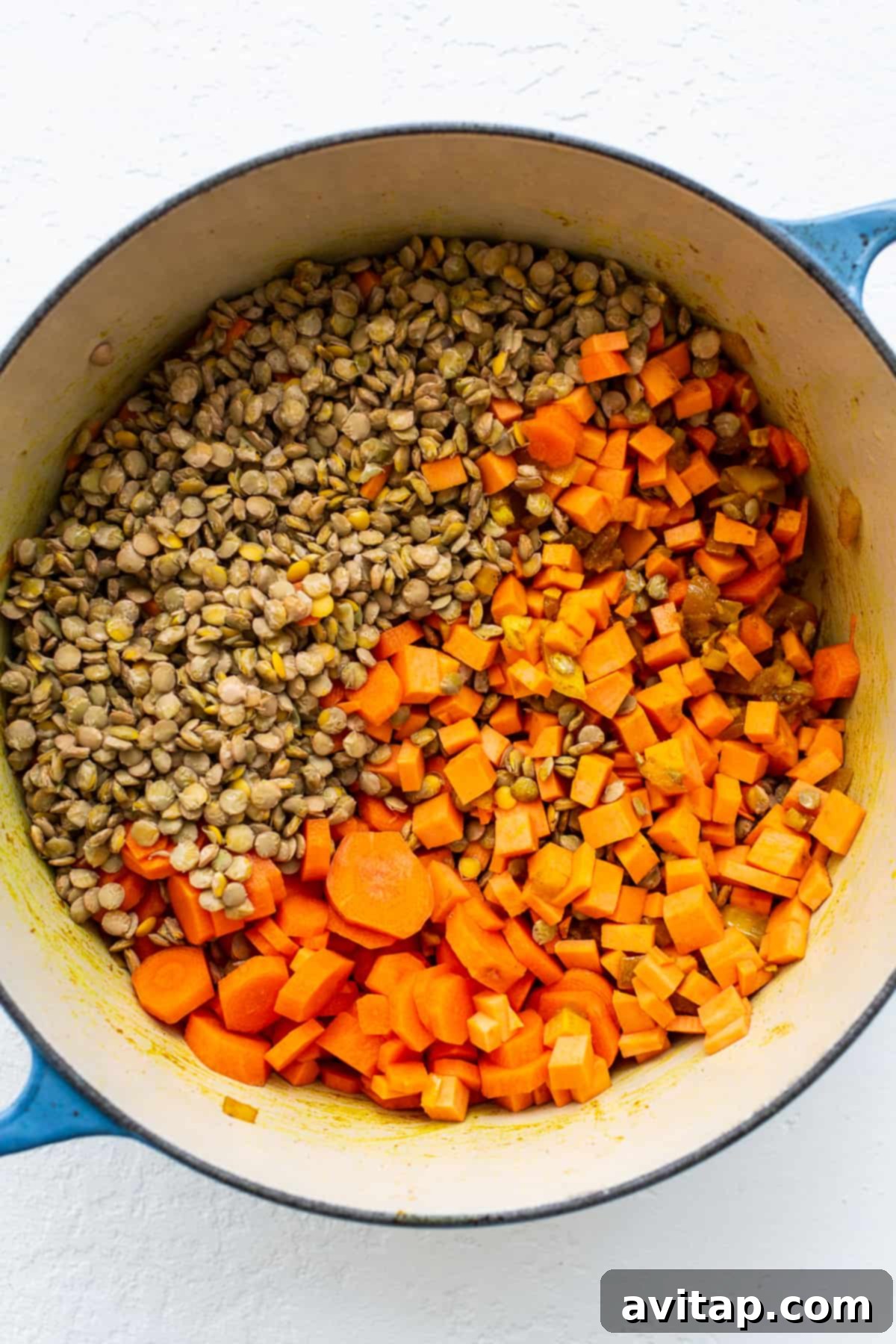 Sweet potatoes and lentils cooking in a Dutch oven. Diced sweet potatoes and lentils in a dutch oven.