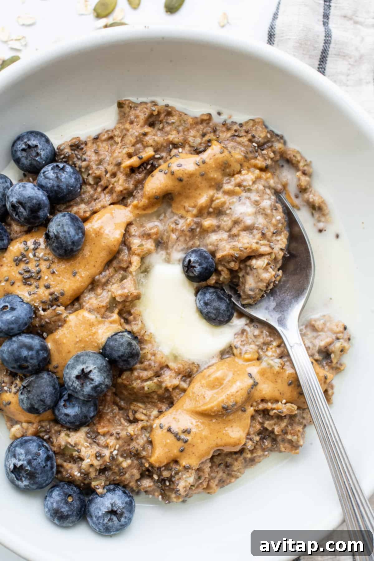 A vibrant bowl of porridge elegantly topped with a medley of fresh fruit and a swirl of creamy nut butter.