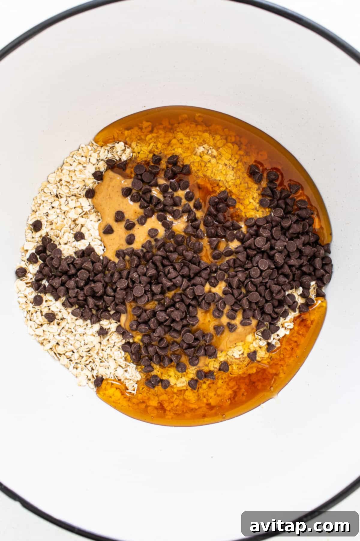 Ingredients for monster cookie oat cups being mixed in a bowl, showcasing the oat layer texture.