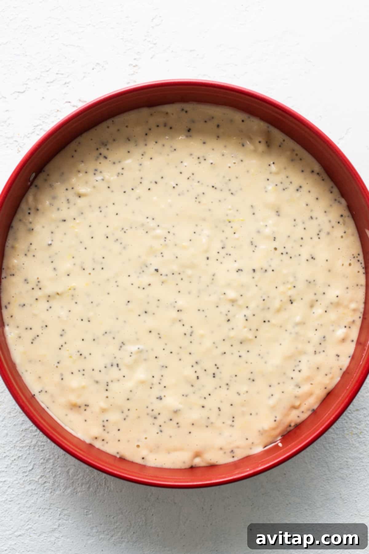 Lemon poppy seed cake batter in a pan, awaiting transformation. Lemon poppy seed cake batter in a cake pan, ready for baking.