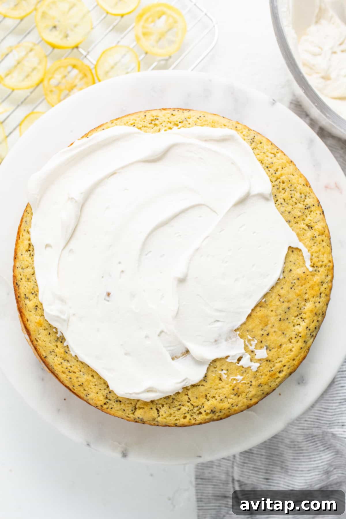A freshly frosted lemon poppy seed cake. Lemon poppy seed cake topped with airy whipped cream frosting.