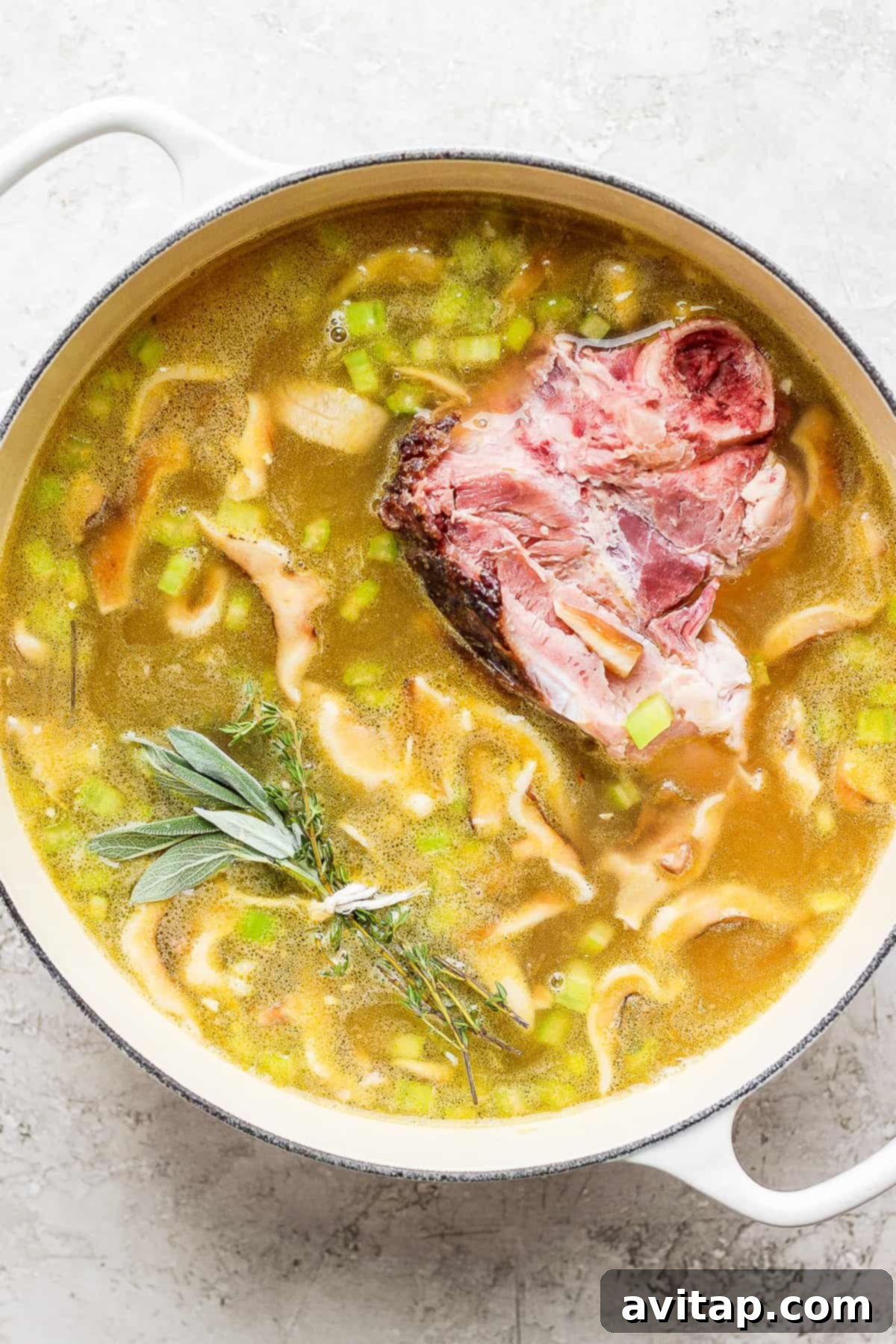 Rich and smoky split pea soup with a ham bone simmering gently in a Dutch oven, herbs infused, promising a hearty meal.