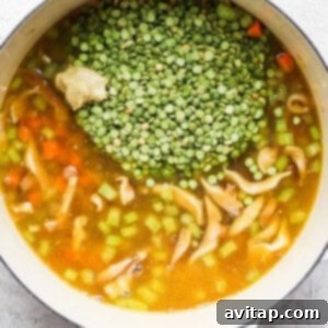 A pot of soup with peas and mushrooms, liquid added.