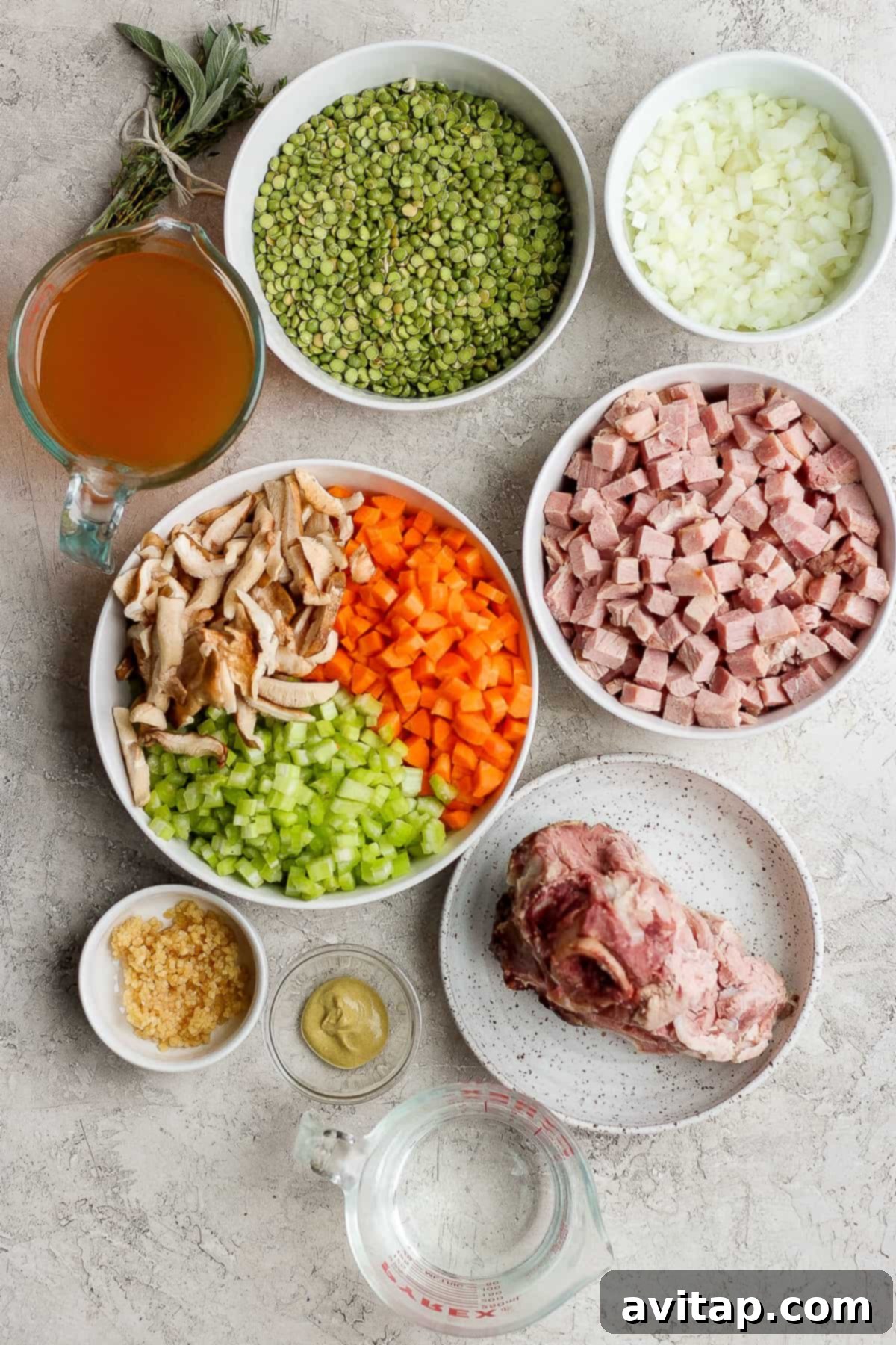A vibrant selection of ingredients for split pea soup with ham, including dried green split peas, diced ham, fresh carrots, celery, onions, garlic, and shiitake mushrooms, neatly arranged in bowls.