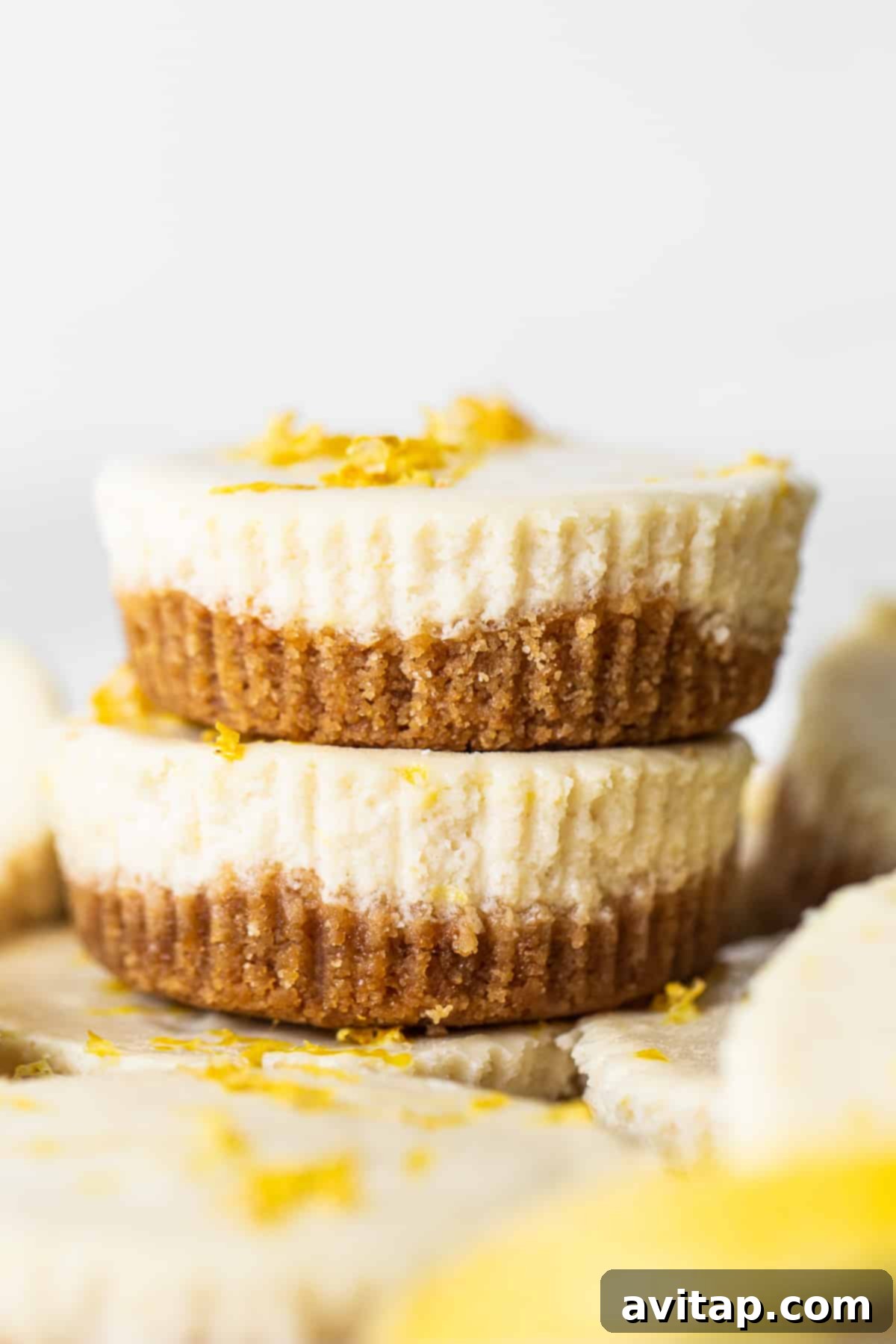 This mini cheesecake recipe is made with a sweet and salty crust, cream cheese, honey, vanilla, and lemon zest making them the perfect Spring dessert. stack of cheesecakes.