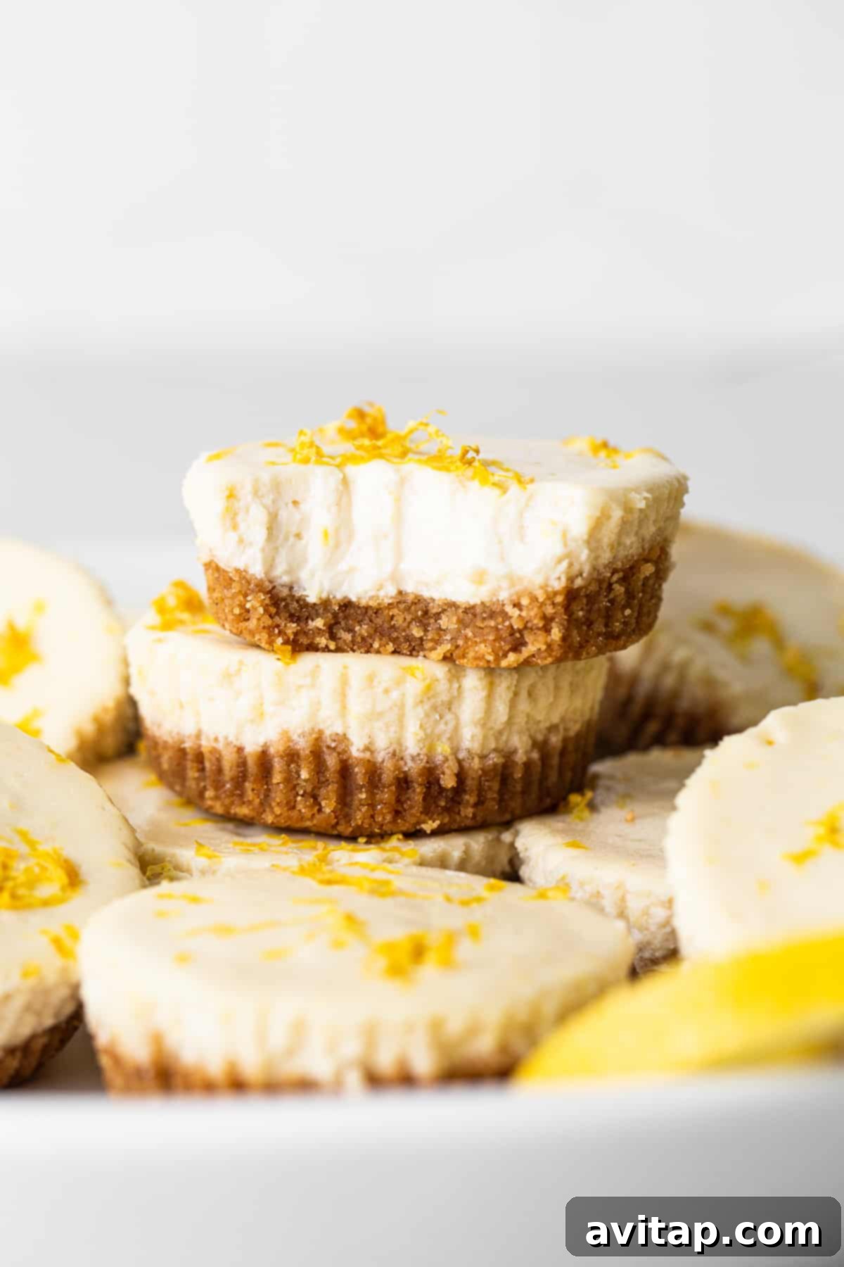 This mini cheesecake recipe is made with a sweet and salty crust, cream cheese, honey, vanilla, and lemon zest making them the perfect Spring dessert. stack of cheesecakes.