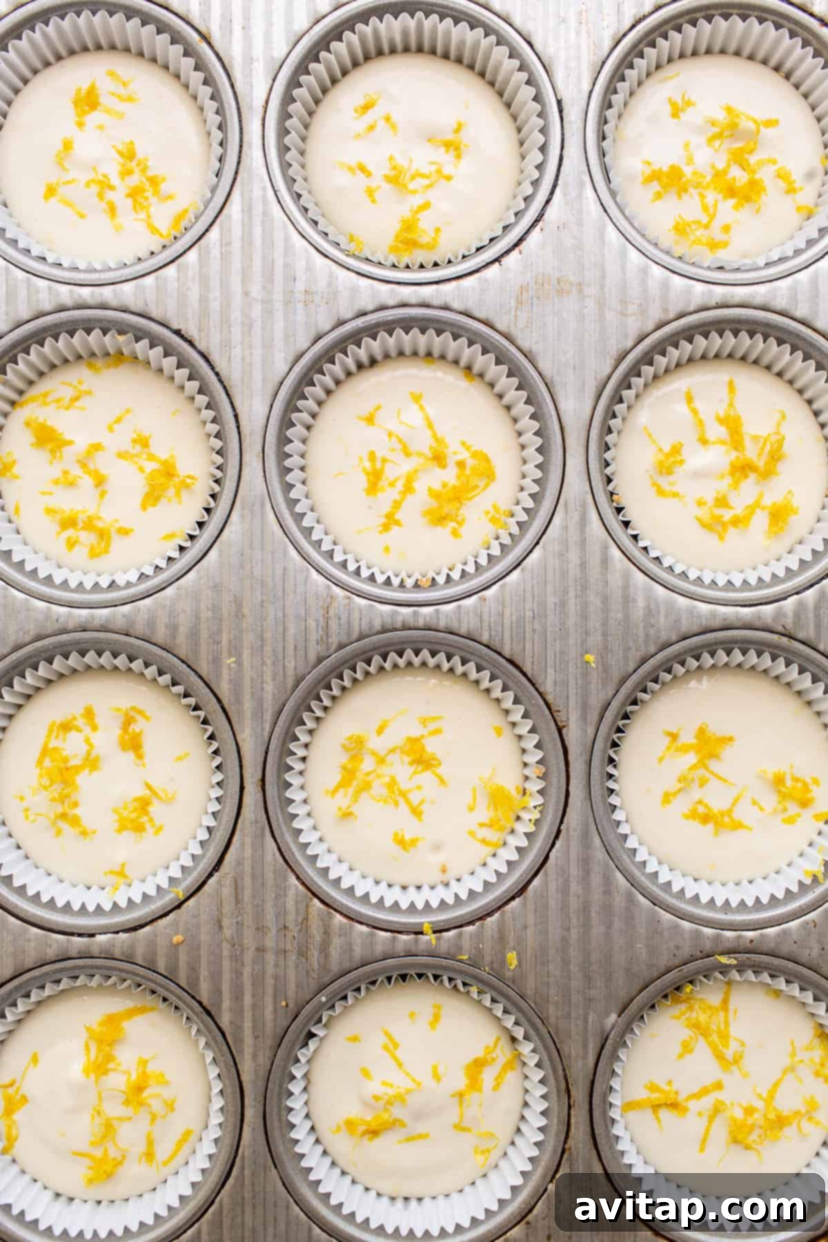 This mini cheesecake recipe is made with a sweet and salty crust, cream cheese, honey, vanilla, and lemon zest making them the perfect Spring dessert. cheesecake cups in muffin tin.