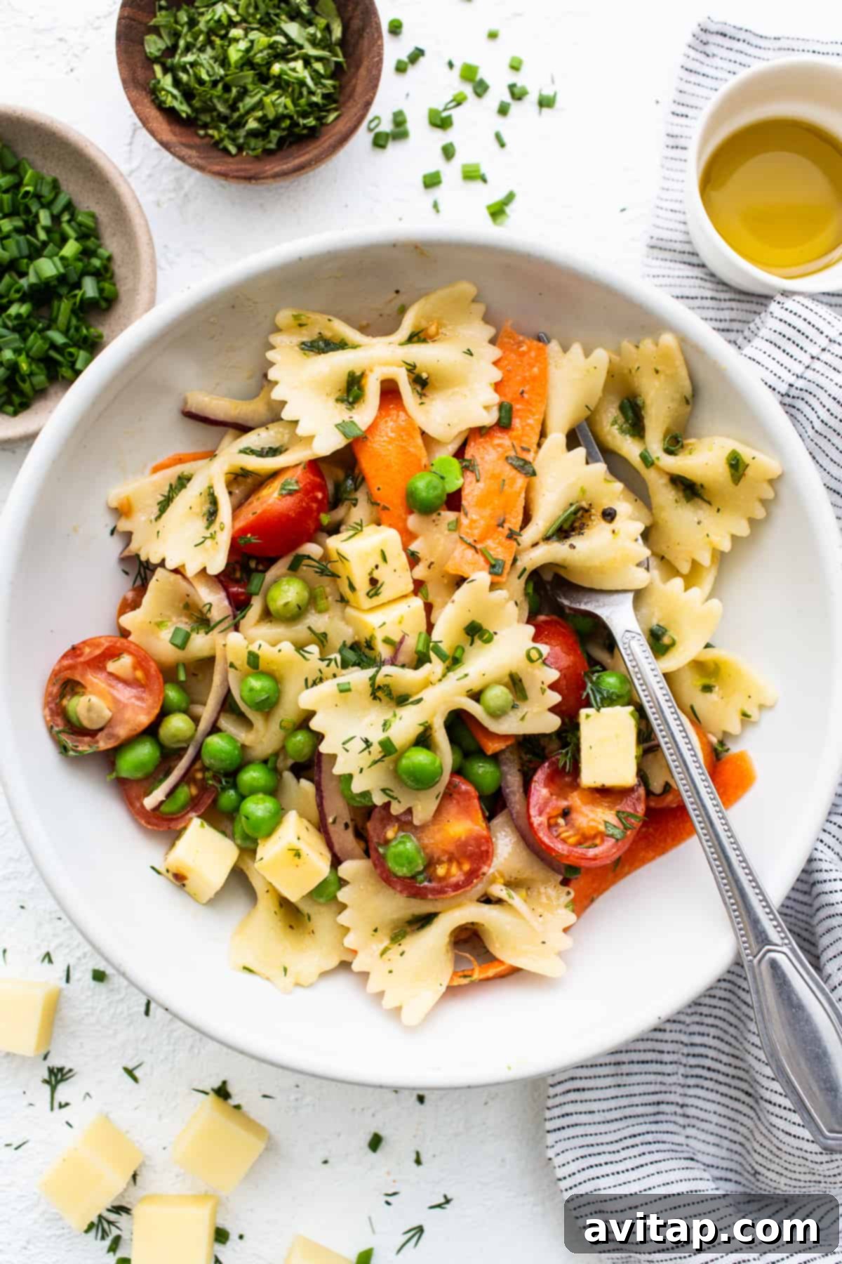 A large bowl of bow tie pasta salad, garnished beautifully with a generous sprinkle of fresh herbs on top, highlighting its fresh and inviting presentation.