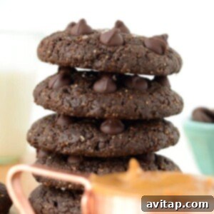 A stack of Double Chocolate Peanut Butter Cookies on a wooden cutting board, ready to be served.