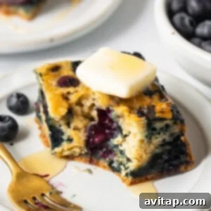 Blueberry breakfast cake sliced on a plate with a fork, ready to be enjoyed.