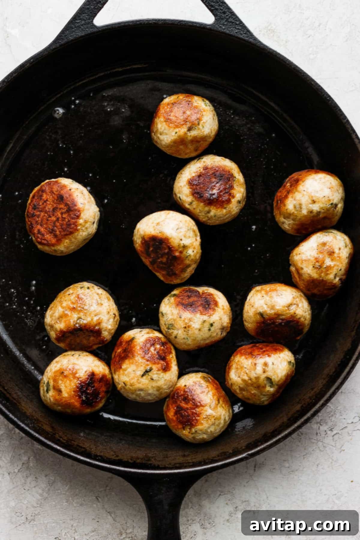cooking meatballs in cast iron pan.
