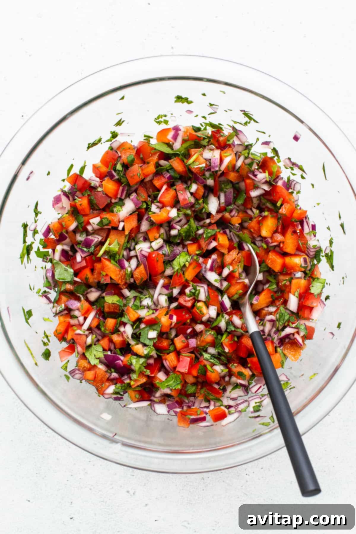 Freshly made pico de gallo in a glass bowl, showcasing vibrant colors of tomatoes, onions, and cilantro.