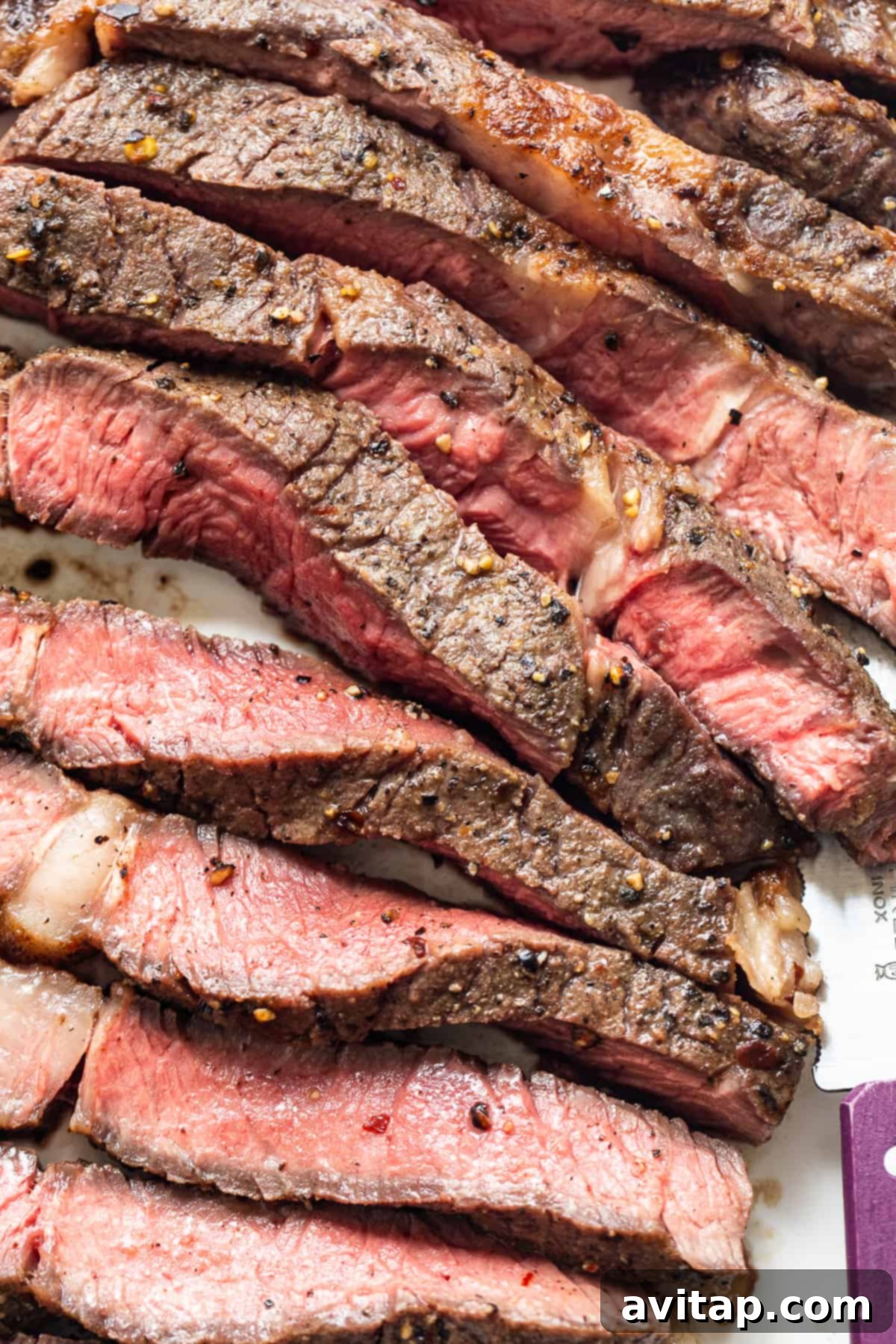 Expertly sliced steak, displaying its tender texture and perfect cook, resting on a clean surface.
