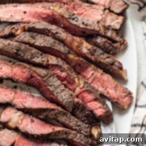 A perfectly cooked air fryer steak on a white plate with a fork.