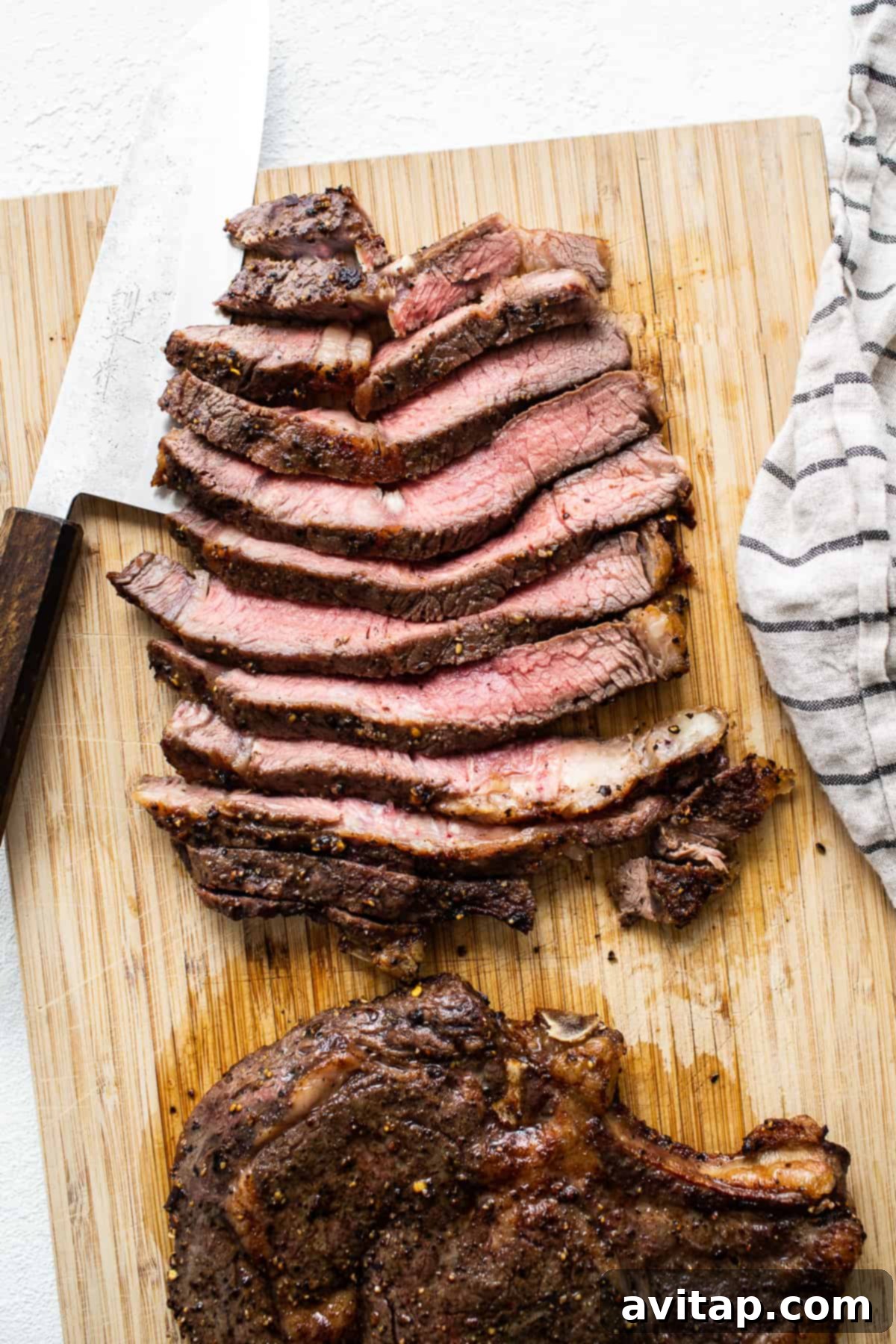 Freshly cooked, sliced air fryer steak resting on a cutting board, perfectly tender.