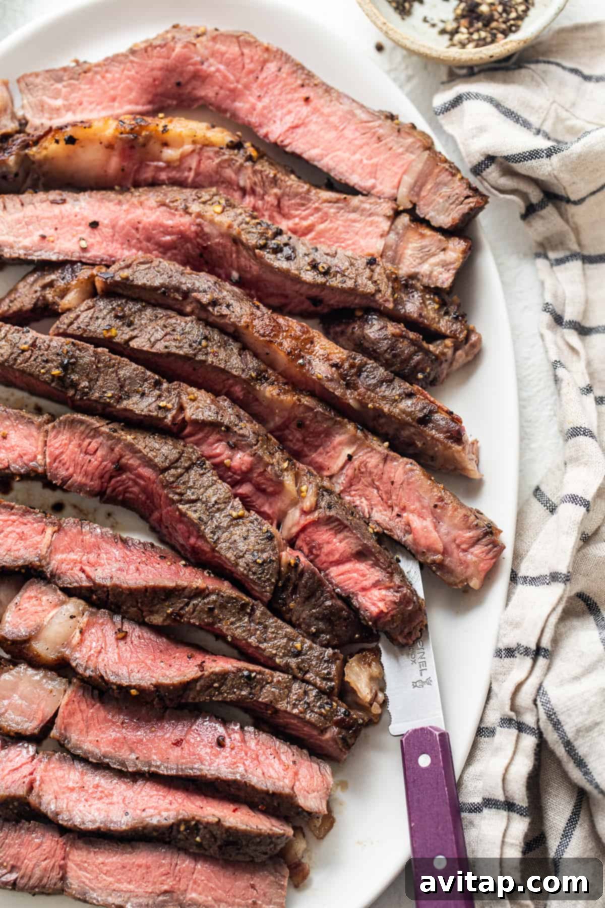 A perfectly cooked air fryer steak on a plate with a steak knife, ready to be carved and enjoyed.