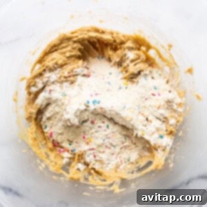 Masa cookie dough balls covered in rainbow sprinkles on a baking sheet.